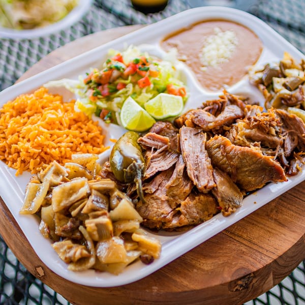 El Arriero Taqueria's Mexican platter with shredded meat, rice, beans, salad, and lime wedges.
