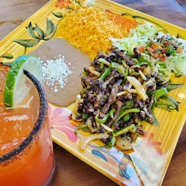 El Arriero Taqueria's fajita plate with rice, beans, salad, and a margarita with a lime.